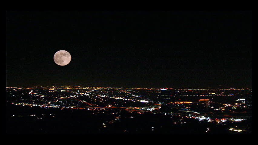Time-lapse shot of L.A. city lights with a full moon.