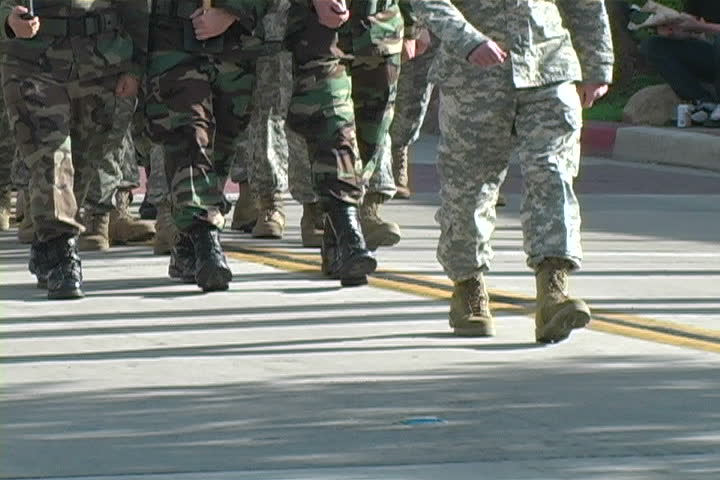 Soldiers marching on a paved road.