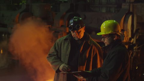 Engineer and Worker Have Conversation in Foundry. Engineer Using Tablet. Industrial Environment.? Shot on RED Cinema Camera in 4K (UHD).