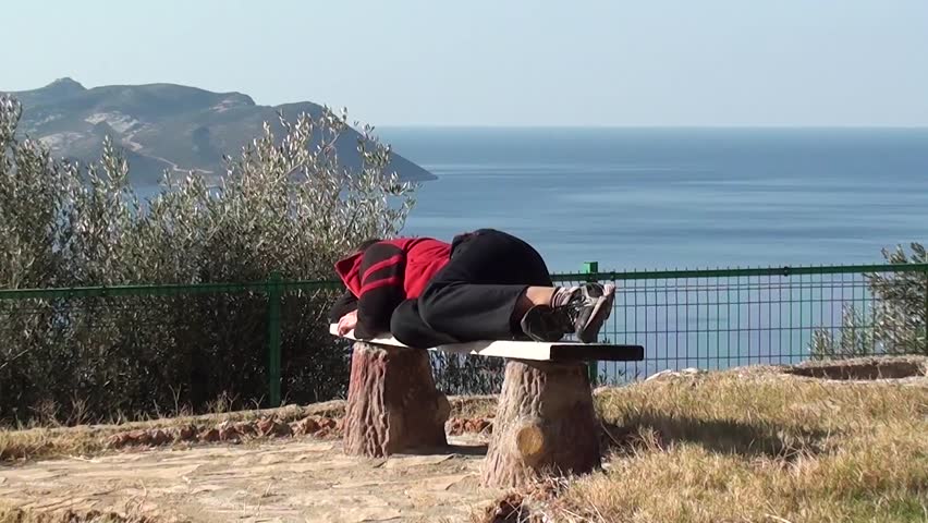 Child comes and wakes up a woman sleeping on the bench at the daytime,  beautiful sea view in the background

