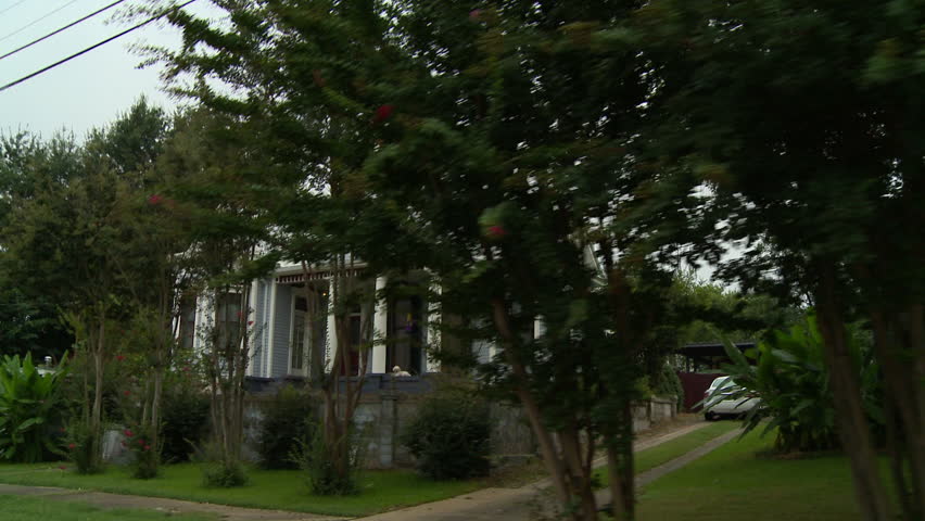 A driving shot of an old victorian house in a small southern town neighborhood in Vicksburg, Mississippi on a hot and muggy summer day.
