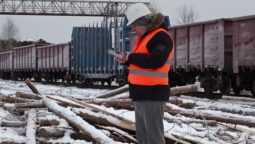 Railway officer using tablet PC near to freight wagons