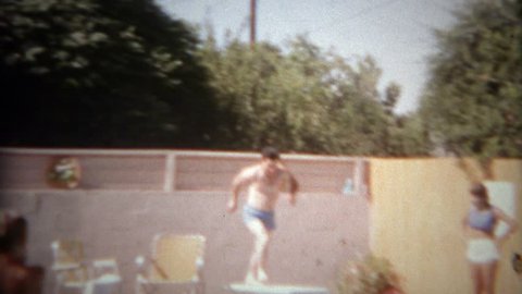 SAN DIEGO, CALIFORNIA 1965: Man falls off springboard in failed attempt at pool diving fun.