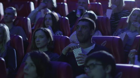 Group of people are scared while watching a horror film screening in a movie cinema theater. Shot on RED Cinema Camera in 4K (UHD).