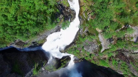 Aerial top-down view of popular Voringfossen waterfall in Norway with visible rainbow on sunny summer day, major tourist attraction on the way down from Hardangervidda. Aerial 4k Ultra HD.
