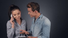 Couple using electronic tablet on grey background