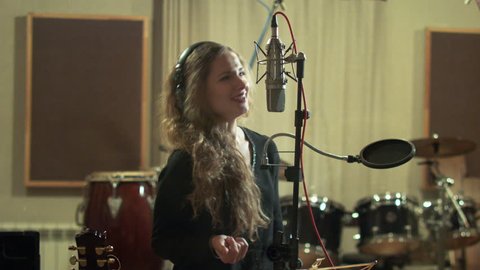 Beautiful girl sings in a recording studio - 4K shot with dolly.