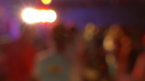 People dance at party in night club with color light, defocused