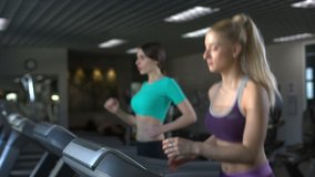 couple of smiling young beautiful girls running on the treadmill