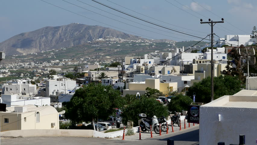 A view of houses, power lines, and a volcano.
