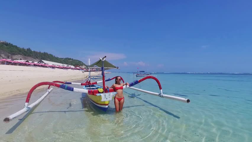 Young and beautiful fashion female model in red bikini lying on the waves in the sea. Fashion shooting. Aerial video in Indonesia Bali. Relaxing on vacation