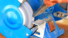 Worker grinding metal component on bench grinder closeup