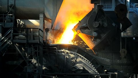  molten metal poured from ladle into mold at steel plant