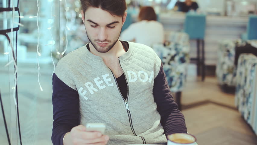 Young man with smartphone sitting in cafe, close-up Royalty-Free Stock Footage #13756172