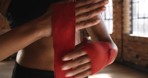 Beautiful Kickboxing woman putting on punching wraps in fitness studio fierce strength fit body