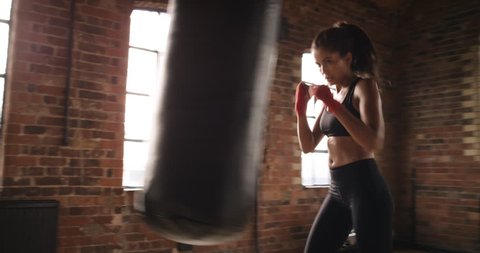 Beautiful Kickboxing woman training punching bag in fitness studio fierce strength fit body kickboxer series