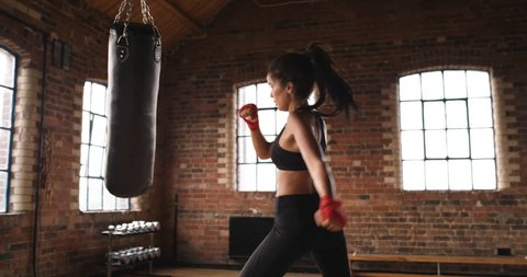 Beautiful Kickboxing woman training punching bag in fitness studio fierce strength fit body slow motion kickboxer series