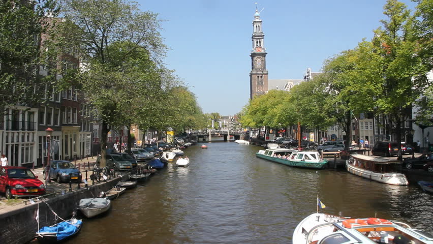 AMSTERDAM, HOLLAND - AUGUST 1: Boats sail in Amsterdam canal under the Westerchurch tower on August 1, 2011 in Amsterdam, Holland. The 17th-century canal ring area is on the UNESCO World Heritage List.