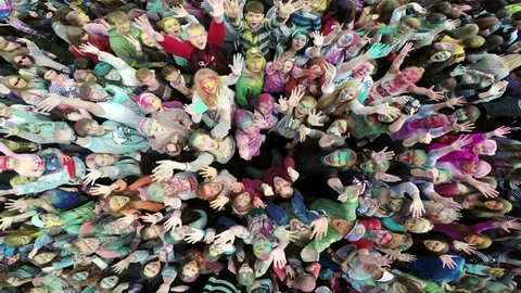 Russia, Chelyabinsk, 13 June 2015: Aerial flight above dancing crowd on Holi Festival Of Colors. Crowd of people colored powder and having fun in arena