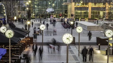 Timelapse of people rushing from work with several clocks in the docklands financial centre in London