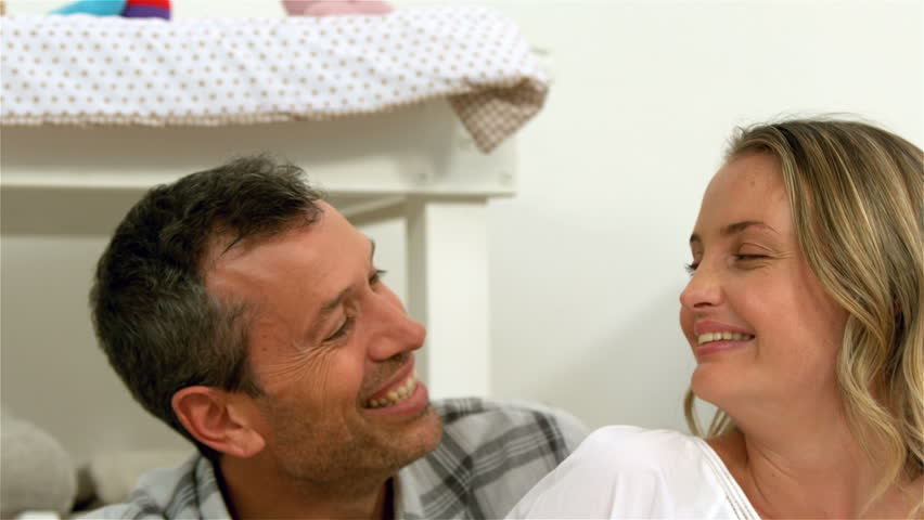 Pregnant woman doing heart with hands with husband at home