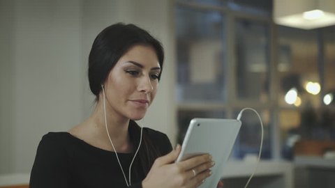 A woman in the office talking with a tablet and smiles