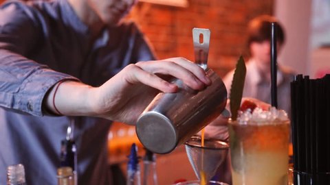 Barmen hand with shaker pouring cocktail