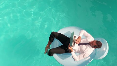 Businessman using laptop on inflatble in slow motion
