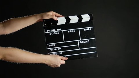 Hands with movie production clapper board, on black