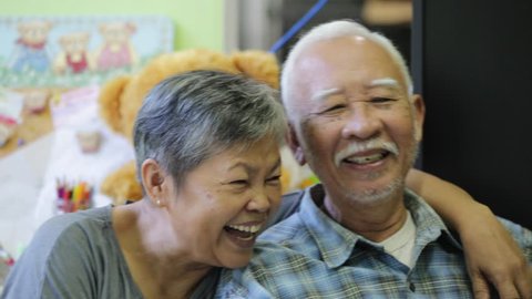 Happy asian senior man and woman hugging and smiling in front of camera.