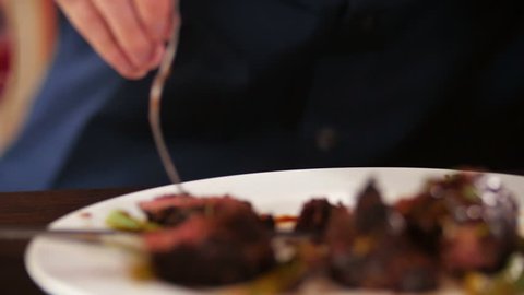 man cuts off a piece of steak close-up