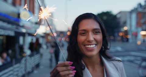 Beautiful Indian Woman walking with sparkler in the city having fun smiling celebration