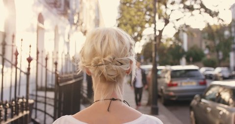 Beautiful blonde walking though city on journey to destination from behind