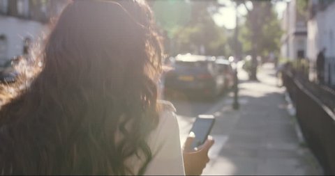 Beautiful Indian woman walking through city living happy lifestyle using smart phone reading social media