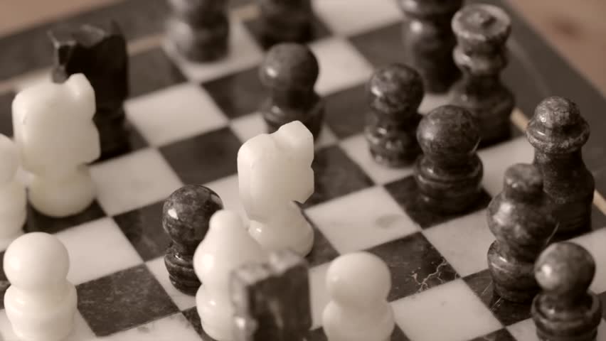 A closeup of a man playing chess on a cool marble chess board