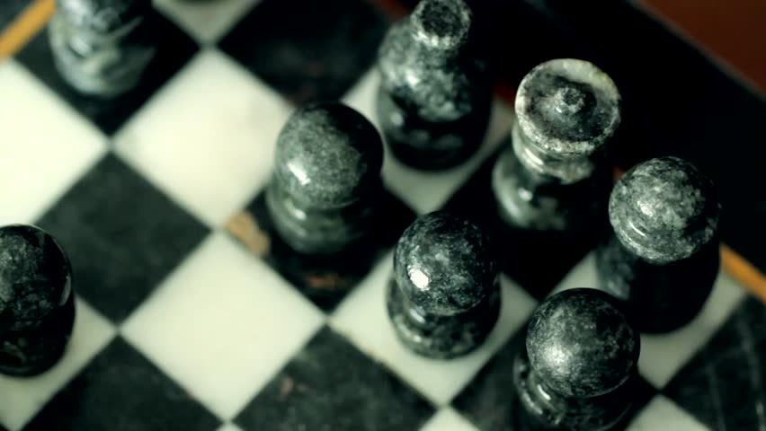 A closeup of a man playing chess on a cool marble chess board