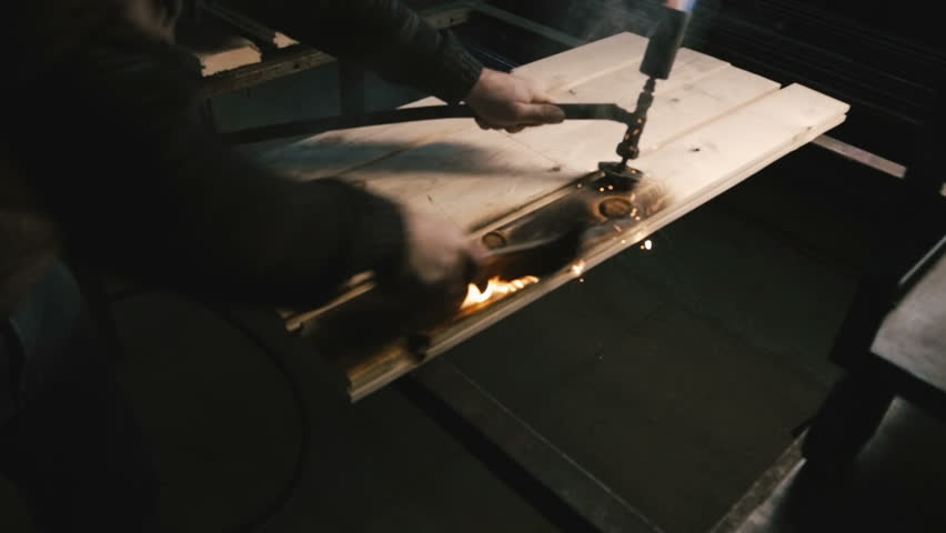 Carpenter grinds burning wood. Close-up.