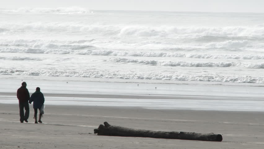 Older man and woman walking on the Oregon Coast stop and give each other a romantic kiss.