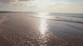 Aerial drone video of sea waves breaking on sunny day. Tracking shot fit woman standing with hands on hips at shore. This footage is filmed from a high angle perspective.
