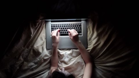 Woman fallen asleep with her computer on the bed