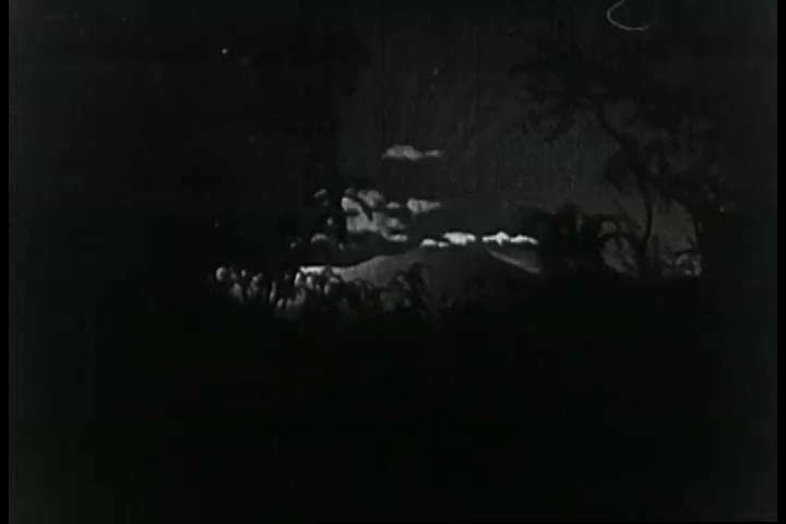 CIRCA 1920s - At sunrise, we can see men paddling two boats on a river through a jungle, a tiger watching in 1925.