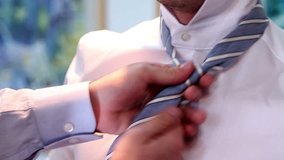 Groom preparation before wedding. Indoor video of man in suit with blue-white lines tie