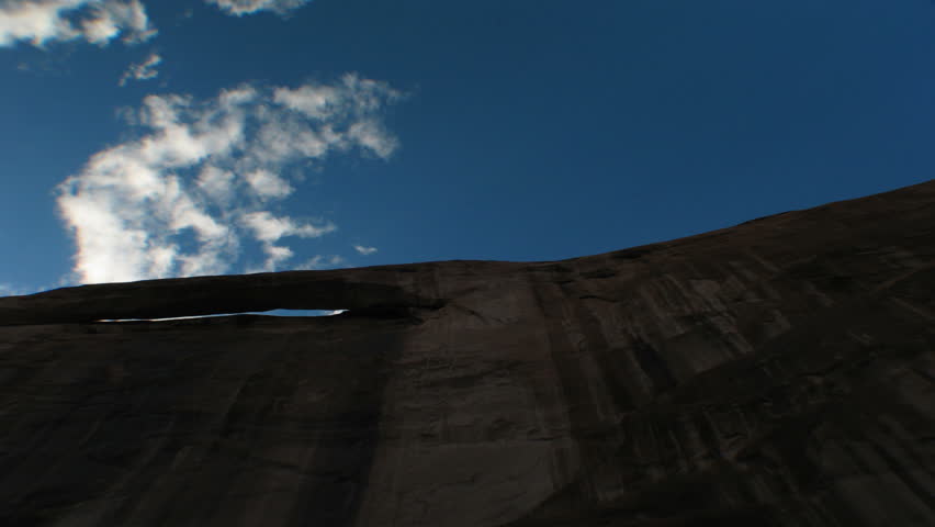 Time lapse white clouds roll in over a sheer rock cliff.