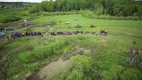 Russian Federation, Siberia. Competitions off-road vehicles on the track among the trees and green grass. Aerial video shooting.
