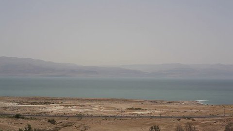 Truck and cars drive on road next to the Dead Sea desert, Israel