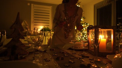 4k footage, slow dolly move woman in festive dress putting cutlery on nicely decorated dining table on christmas eve at home, captured with atomos shogun
