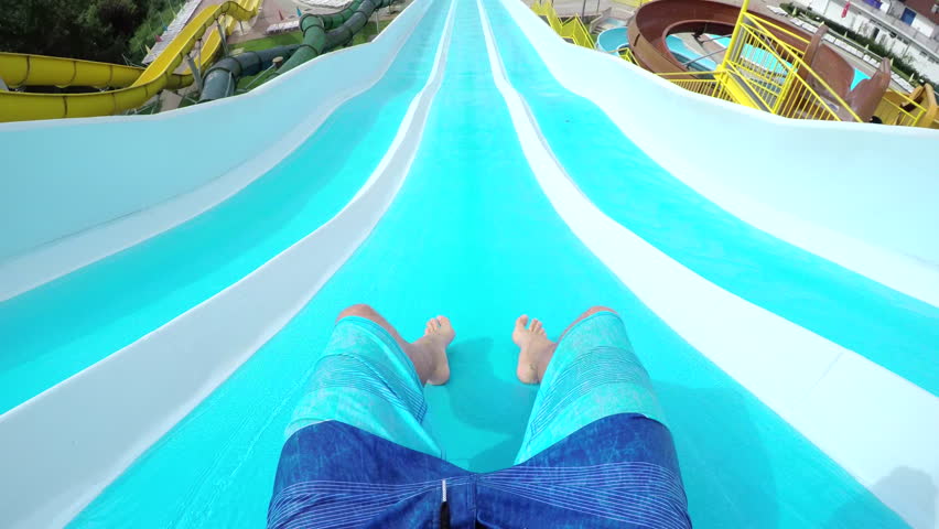 FPV: Man sliding down extreme fast water slide toboggan on a fun summer day