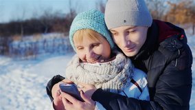 Mother and son read from the screen of the smartphone, smiling