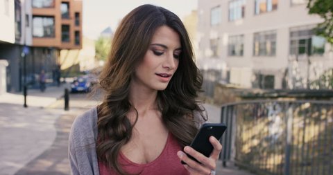 Beautiful woman using smart phone technology app walking through city streets living urban happy lifestyle