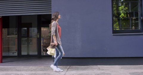 Beautiful woman carrying shopping bags walking through city shopaholic retail lifestyle